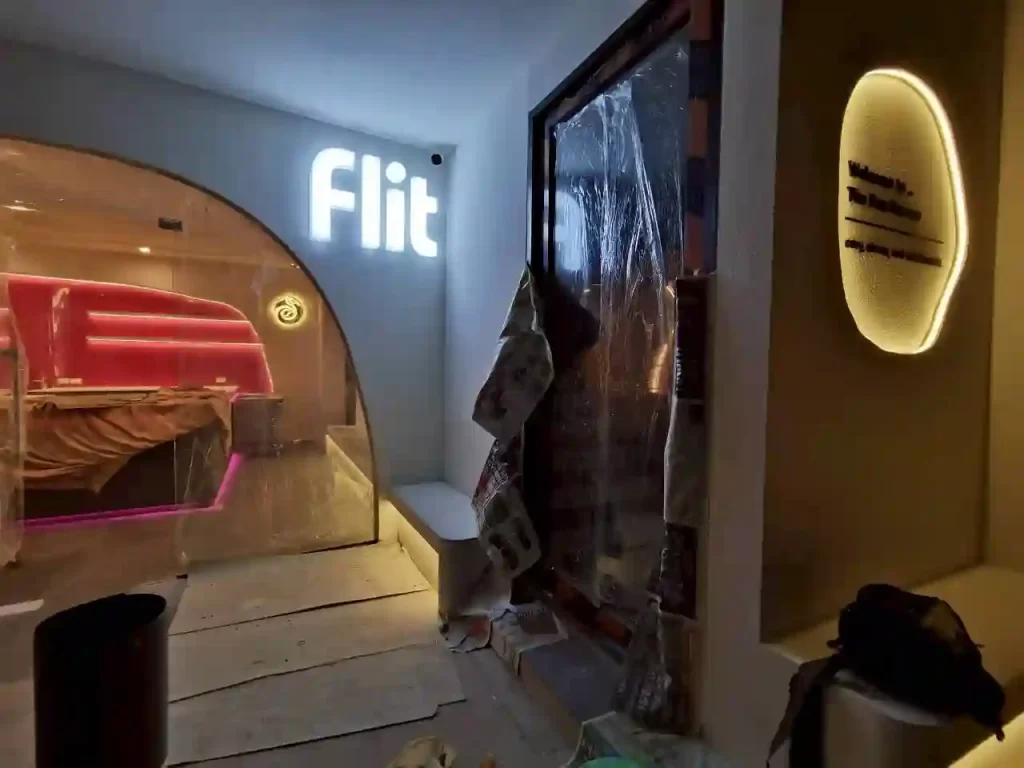 ป้ายไฟ Flit ตัวอักษรขาวส่องสว่าง และป้ายต้อนรับทรงรีไฟ LED ร้าน Flit Cafe วัชรพล ระหว่างติดตั้ง มองเห็นโซนนั่งไฟนีออนชมพู