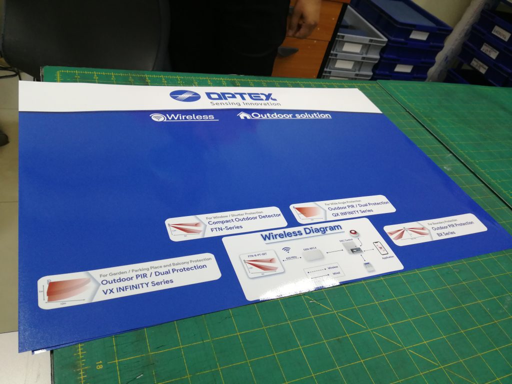 บอร์ดนำเสนอ OPTEX Sensing Innovation พิมพ์ UV บนแผ่นโฟมบอร์ด พื้นสีน้ำเงิน แสดงผลิตภัณฑ์ Wireless & Outdoor Solution ผลิตโดย Scinage