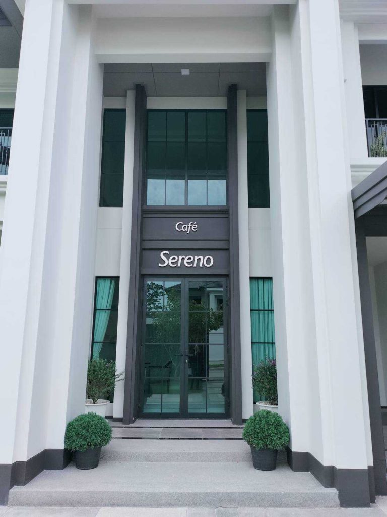 ป้ายตัวอักษรสแตนเลสนูน Café Sereno ติดเหนือประตูกระจกทางเข้า อาคารสไตล์โมเดิร์นคลาสสิกสีขาว ผลิตโดย Scinage