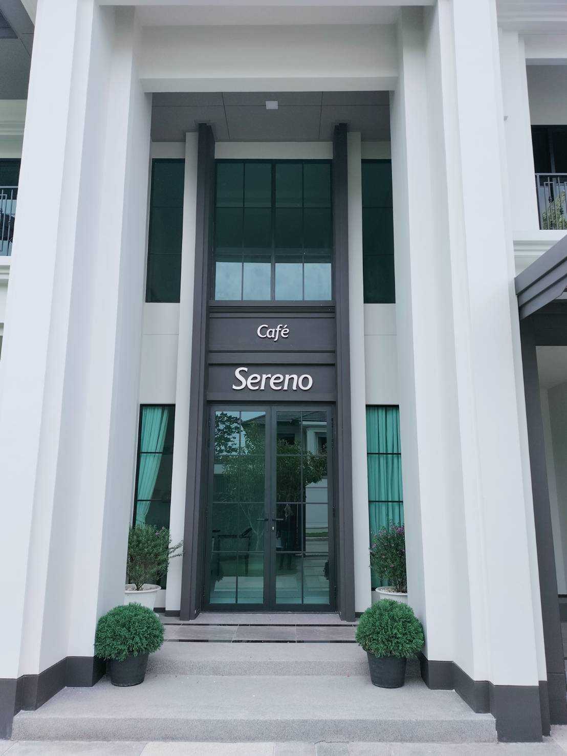 ป้ายตัวอักษรสแตนเลสนูน Café Sereno ติดเหนือประตูกระจกทางเข้า อาคารสไตล์โมเดิร์นคลาสสิกสีขาว ผลิตโดย Scinage